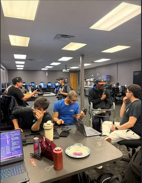 Members talking over open laptops in the campus computer lab